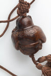 Vintage hardwood carved bead depicting a boy peering into a lidded rice bowl. with cord and tassel. China 1970's. 