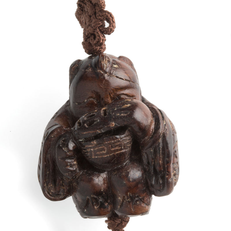 Vintage hardwood carved bead depicting a boy peering into a lidded rice bowl. with cord and tassel. China 1970's. 