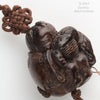 Vintage hardwood carved bead depicting a boy peering into a lidded rice bowl. with cord and tassel. China 1970's. 